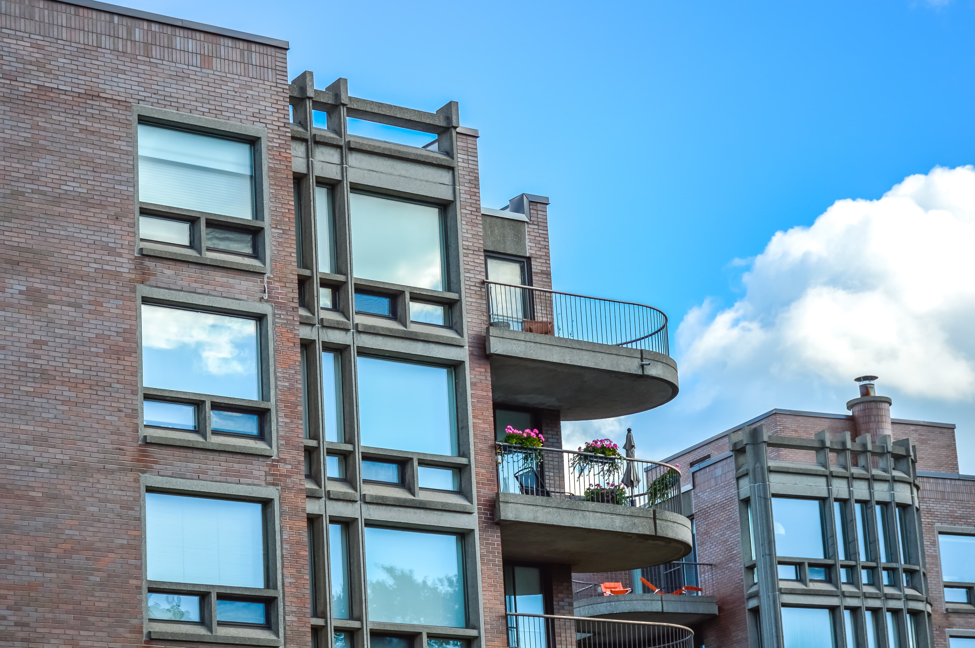 Modern brick apartment with balconies against a blue sky.