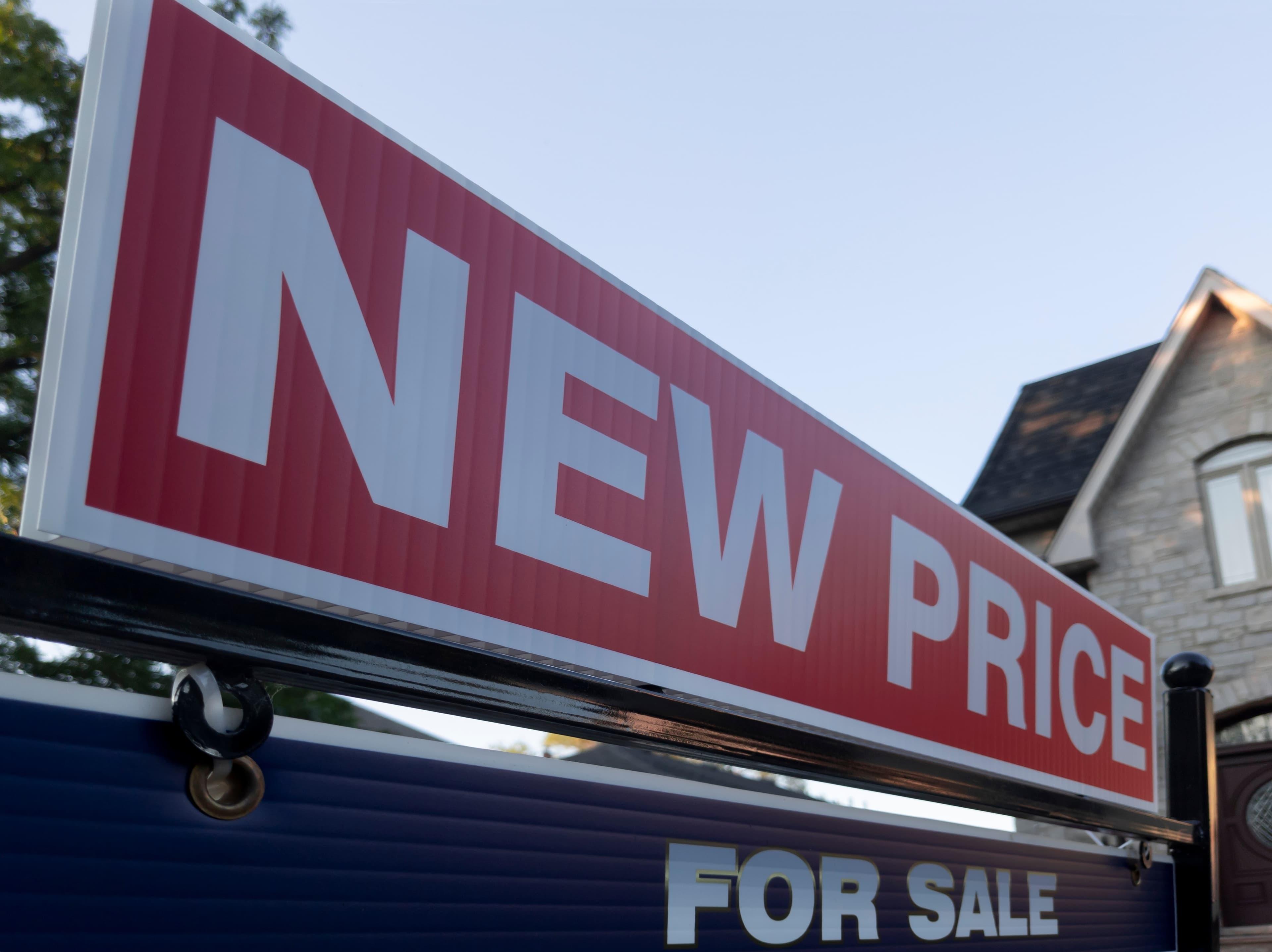 Real estate sign showing 'New Price' in front of a house.