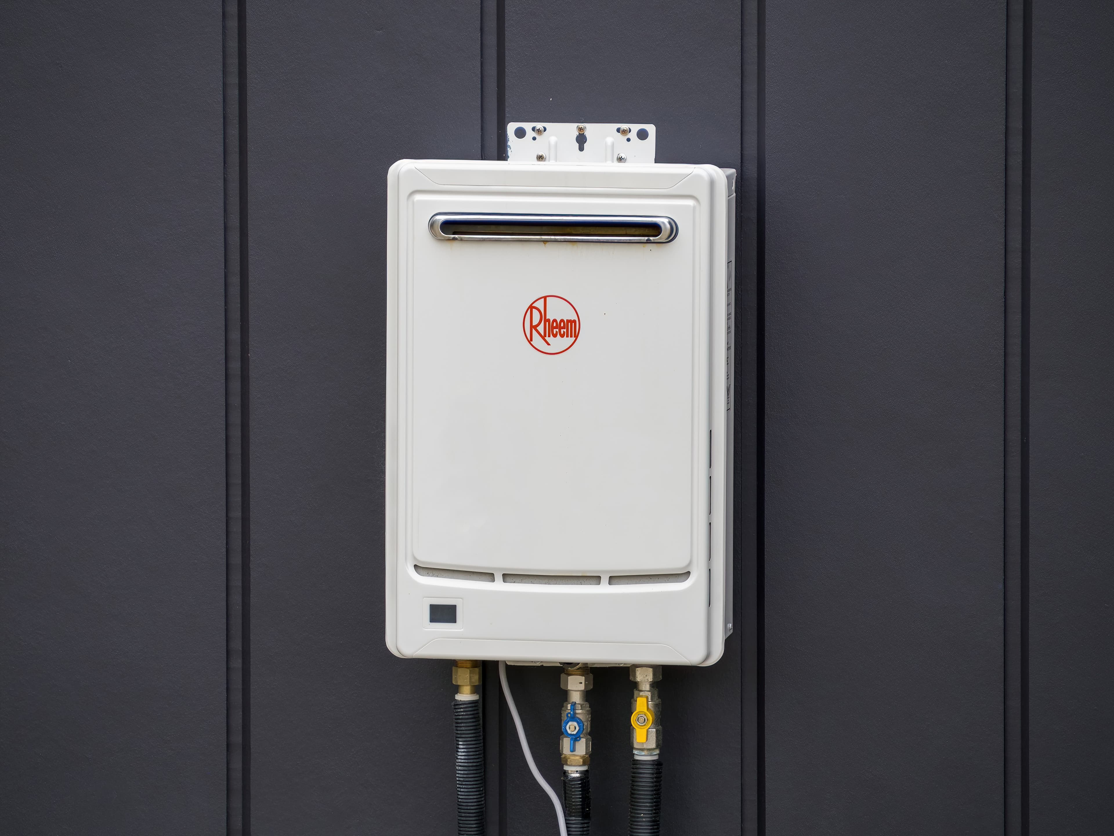 Modern tankless water heater on dark wall.